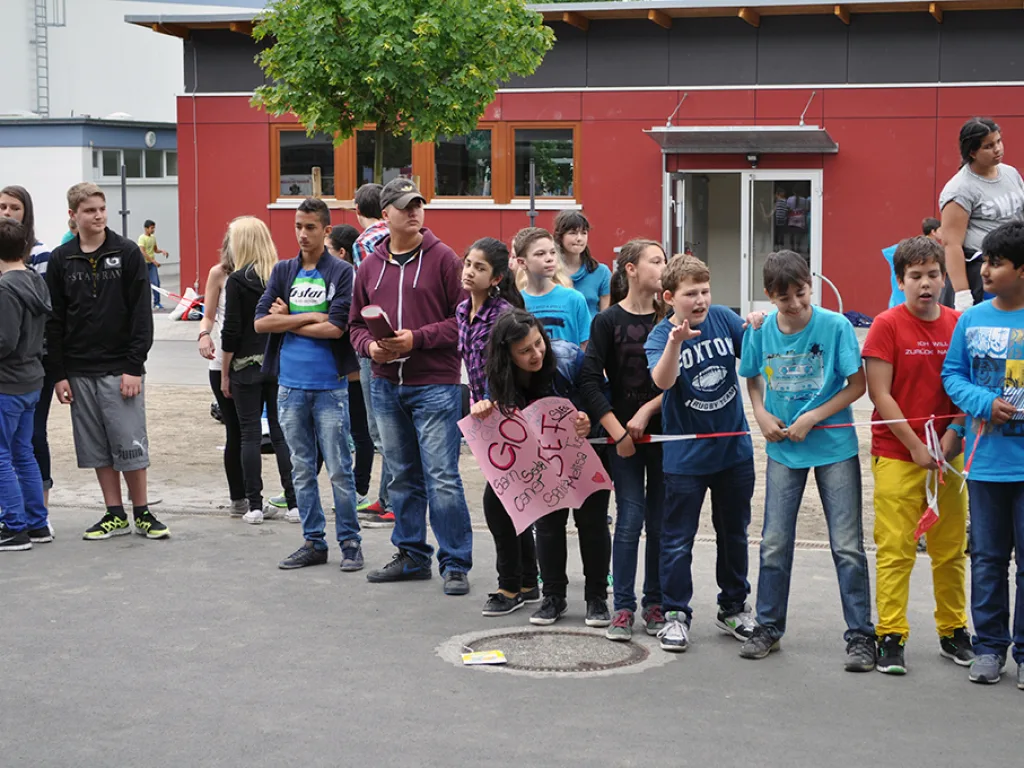 Zuschauer stehen mit Plakaten am Streckenrand.